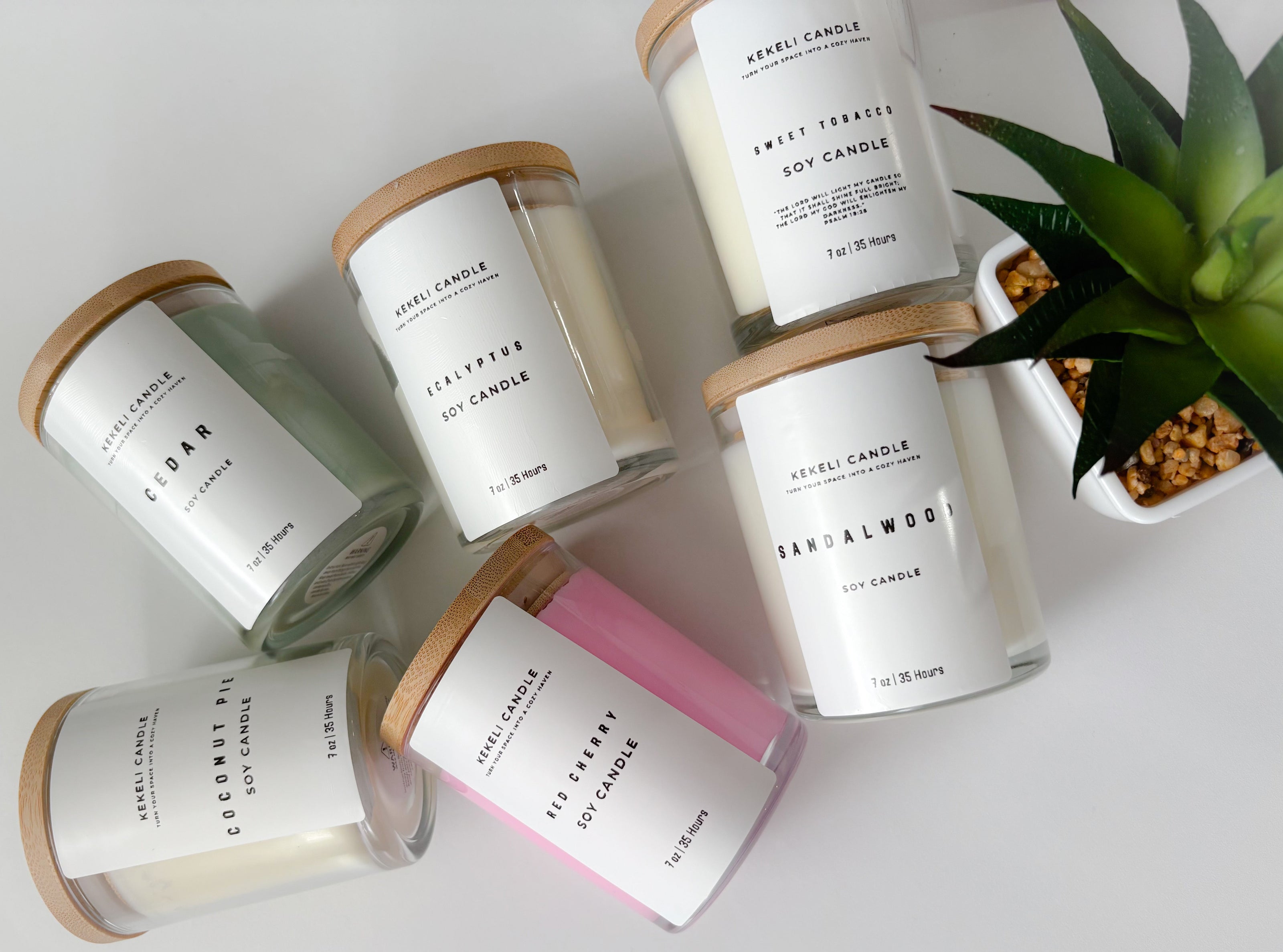 Set of candles with labels on a white surface, one with a pink label.